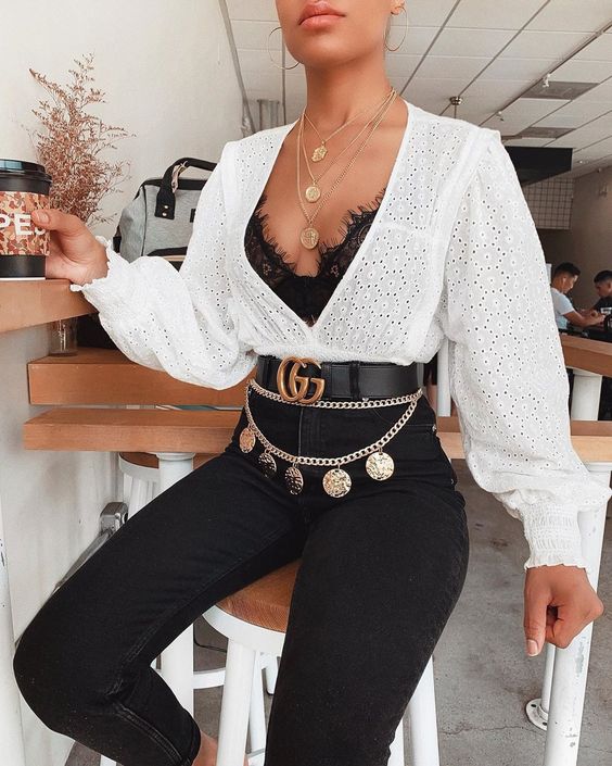 a black lace bra a white perforated shirt black skinnies a gold chain belt with pendants
