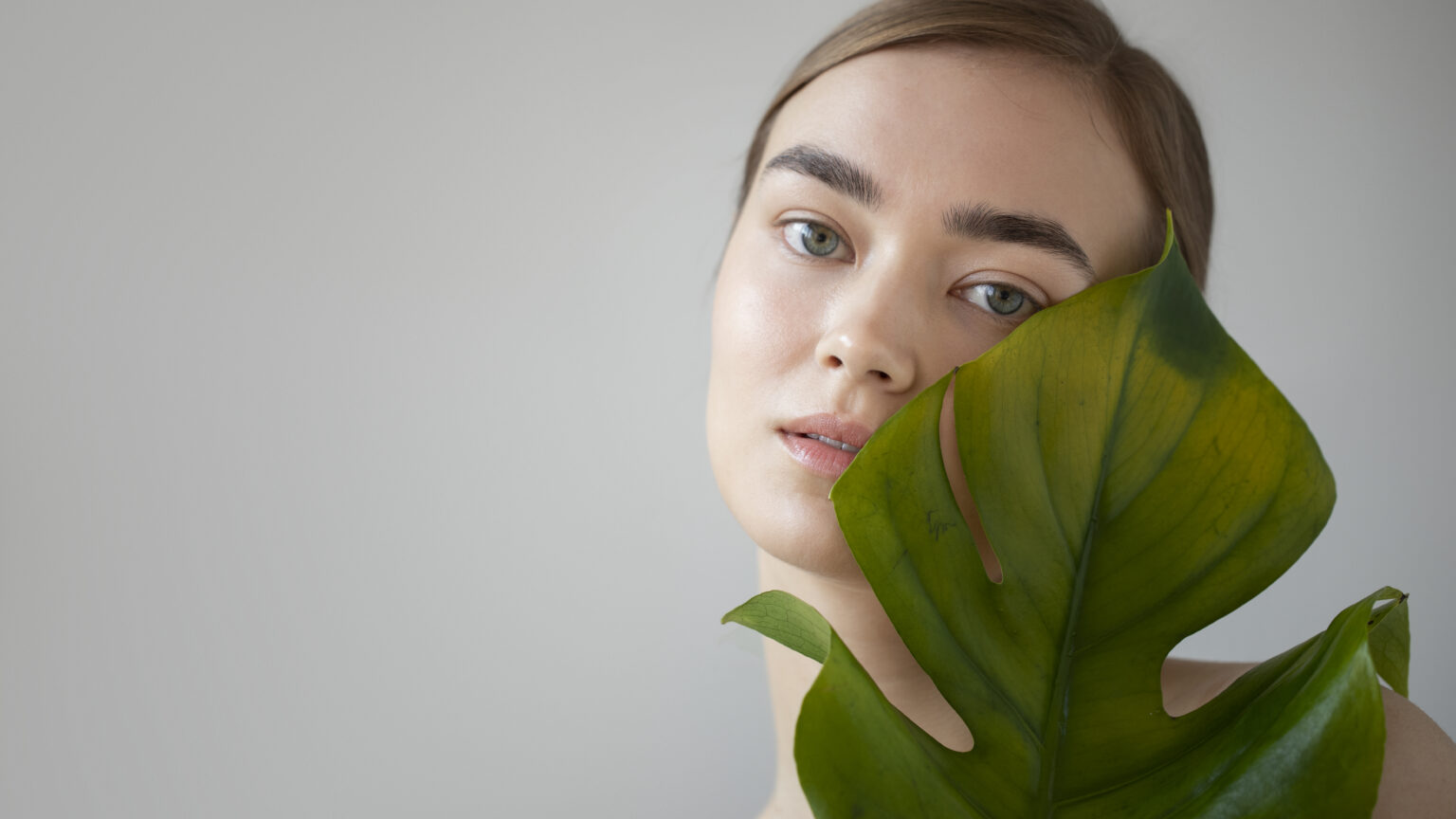 portrait beautiful woman with clear skin posing with monster plant leaf