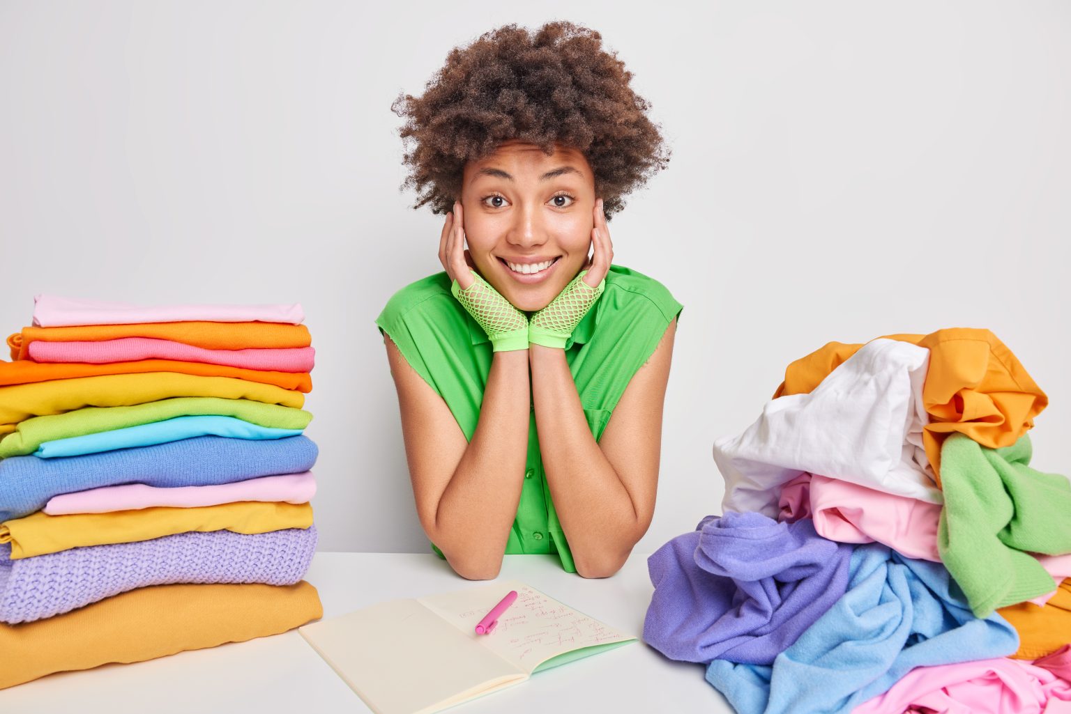 woman green blouse sits table folds clothes after washing drying makes notes notepad writes down list weekends busy doing housework domestic chores